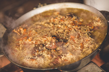 Cooking plov in the cauldron. Only meat, onions and carrots in the cauldron. Field kitchen. Eastern cuisine.
