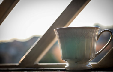 Porcelain tea or coffee cup by the window, backlit