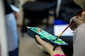 Paintbrush mixing oil paints. Artist paints a picture of oil paint brush in hand with palette close up.