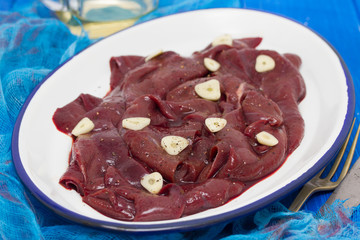raw liver on white dish on wooden background