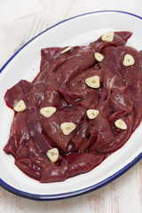 raw liver on white dish on wooden background