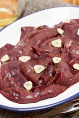 raw liver on white dish on wooden background