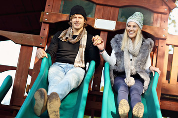 Joyful couple having fun at sliding board outdoors