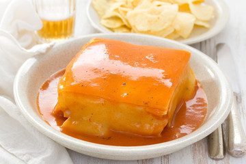 traditional portuguese sandwich with sauce francesinha on dish