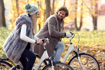 Happy couple on bikes in forest during fall time