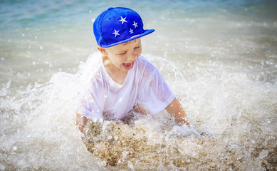 Happy caucasian boy is bathing in sea on summer vacation. Smiling child in sea water