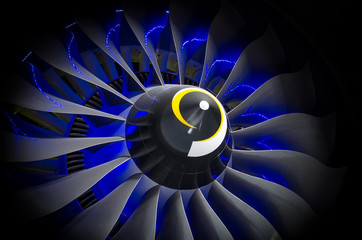 Airplane engine and blades with blue backlight close up black shadow background.