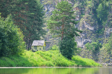 Home at nature, small tent house near by the river and a big wall of rocks