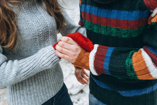 Loving couple in colorful knitted sweaters  without faces only hands