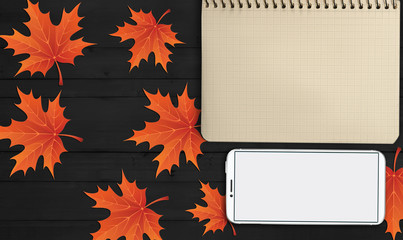 notebook, phone are lying on a wooden table with yellow, autumn leaves - 181540903