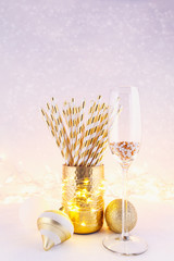Gold and white paper straws in the golden glass. Christmas concept. Festive holiday party background