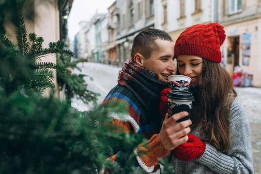 Young loving happy couple with coffee cups on the street in winter