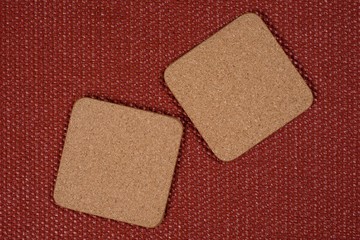 Two square cork stands on a textured terracotta background.