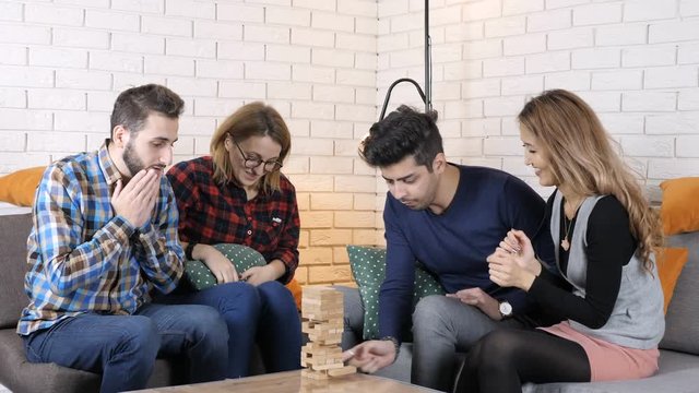 Cheerful company sit on the couch and play jenga board game 50 fps