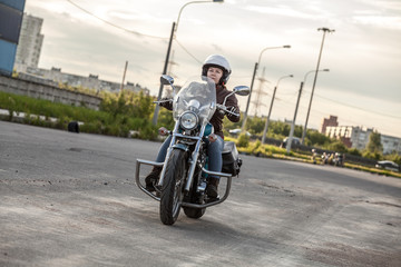 Obraz na płótnie Canvas Female motorcyclist driving solo on asphalt road on motorbike