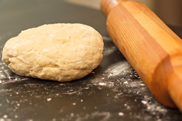 rolling pin and dough on a dark table