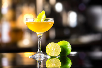 Closeup image of daiquiri cocktail decorated with lemon at bar counter background.