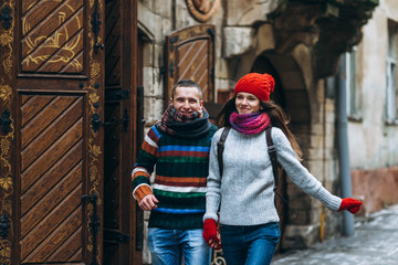 Young romantic couple in knitted clothes having fun outside in winter in the old europian city