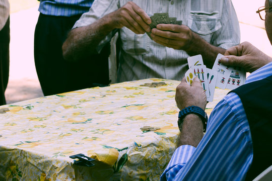 a group of elderly Sicilians playing outdoor with cards