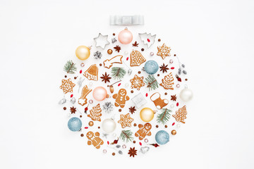 Creative Christmas ball made of gingerbread cookies, baubles, pine cones, stars anise, baking molds, acorns, spruce branches on white background. New Year greeting card concept. Top view.
