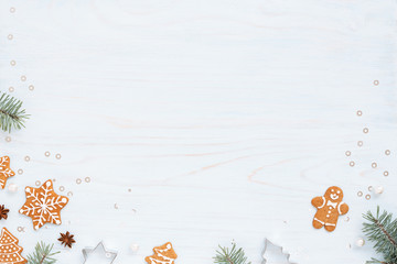 Christmas background with homemade gingerbreads, fir branches and decorations on light blue wooden table. Holiday flat lay. Top view.