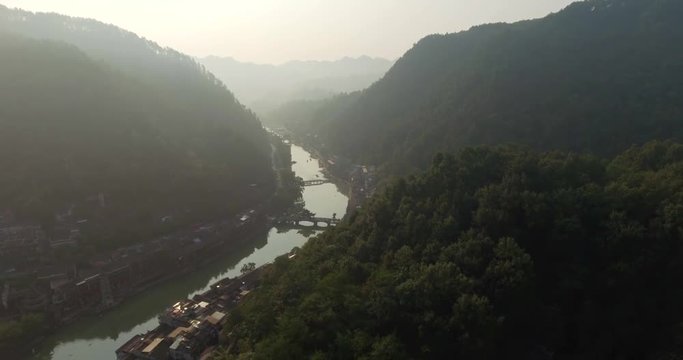 Top view or aerial shot of famous ancient town in Fenghuang County, China. Flying over Green River, hills and houses of the village. Travel,destination and world heritage concept.