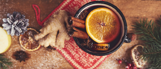 Mulled wine in rustic mug with spices and ingredients on wooden background. Top view, flat lay. Copy space for your text.