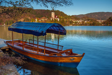 Bled, Slovenia - Traditional blue Pletna boat at Lake Bled with Pilgrimage Church of the Assumption of Maria and Julian Alps at background
