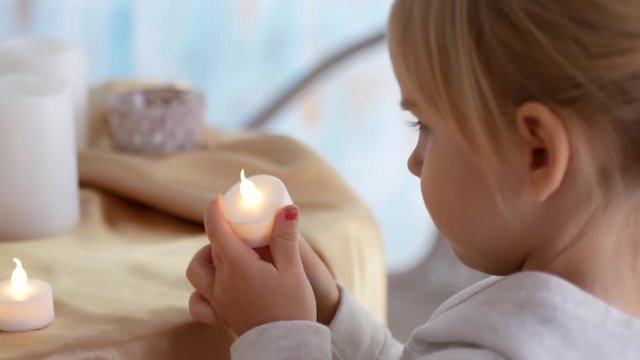 The girl lights up electric candles and puts on the table