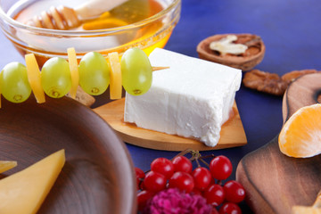 Cheese, soft and hard cheese, fruits, nuts, honey, cheese platter on dark blue background, retro style, pop art, vegan breakfast