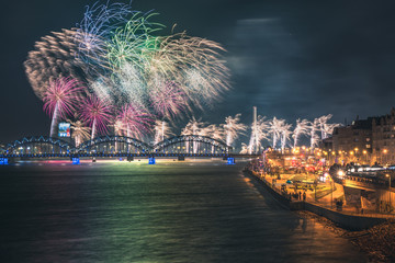 Colorful fireworks in Riga city with panoramic view over the river Daugava and railroad bridge. New year celebration. 