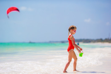 Little girl at tropical white beach making sand castle