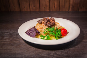 A tasty dish of rice on a plate. On a wooden background