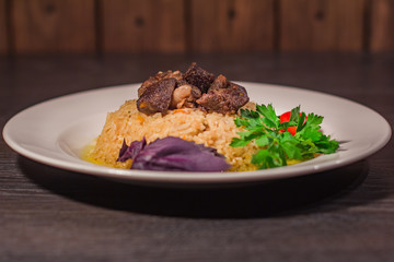 A tasty dish of rice on a plate. On a wooden background