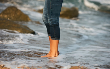 Woman bare foot walking on the beach between rocks
