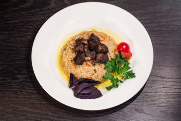 A tasty dish of rice on a plate. On a wooden background