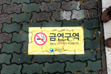 Aufkleber auf Gewegplatten mit dem Zeichen Rauchen verboten, geschrieben mit koreanischen...