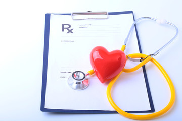Closeup of medical stethoscope on a rx prescription, red heart isolated on white background