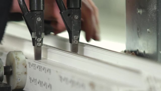 Fastening of a metal skeleton inside plastic profile. PVC window production technology. Factory for PVC windows and doors production. Workers in workshop. Production of plastic windows.