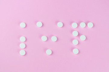 The word IVF, written on a pink background with white tablets. Selective focus.