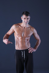 Fototapeta na wymiar muscular man. Muscular man on a grey background showing muscles. Fitness instructor. Fitness professional. Workout. Men's fitness.