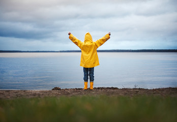 Little Boy in Yellow Rain Coat raising his arms in front of an autumn Lake: He his ready to take on the world and any adventure that comes his way
