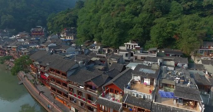 Top view or aerial shot of famous ancient town in Fenghuang County, China. Flying over Green River, hills and houses of the village. Travel,destination and world heritage concept.