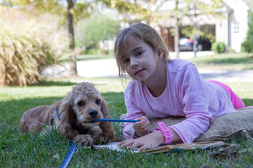 Little girl lying on the grass with her puppy