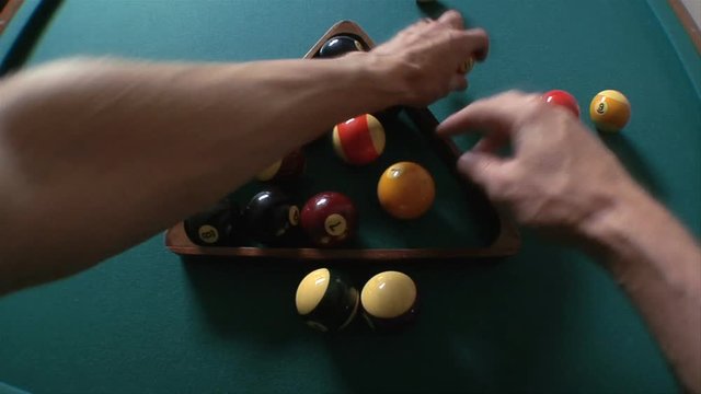 Person racks billiards balls and breaks, close up