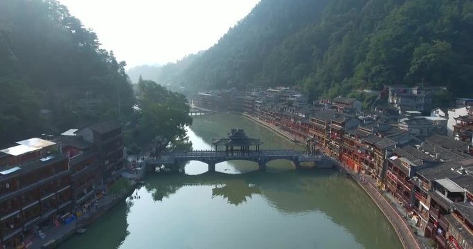 Top view or aerial shot of famous ancient town in Fenghuang County, China. Flying over Green River, hills and houses of the village. Travel,destination and world heritage concept.