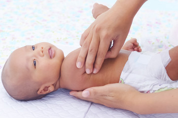 Obraz na płótnie Canvas Mother Gently Massage Her Baby Using Baby Oil