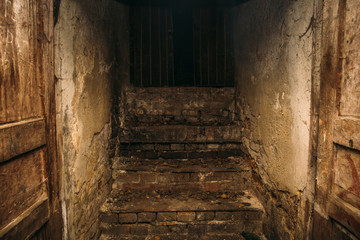 Dirty grunge creepy wooden staircase from abandoned basement, place where homeless people live,...