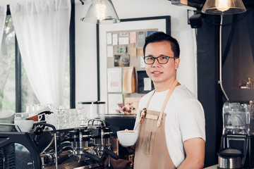 Male Barista cafe owner holding coffee cup in store counter bar inside coffee shop, food and drink business start up