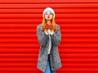Fashion pretty woman blowing red lips sends an air kiss on a background